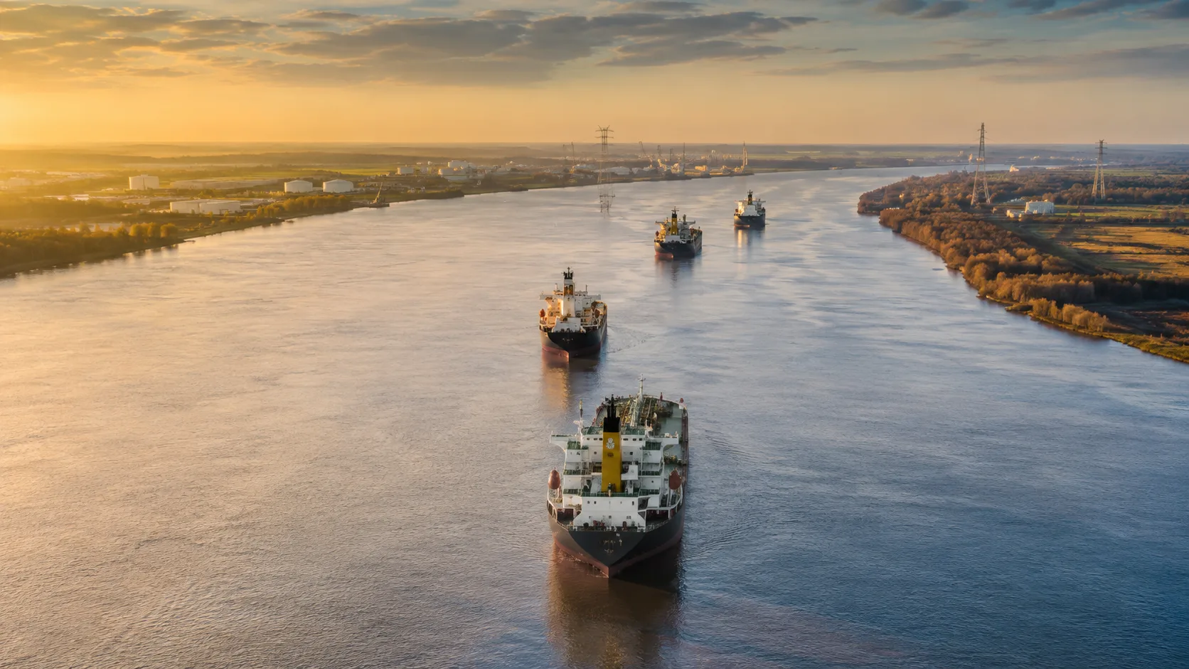 Cargo vessels transiting a river at sunset for Lamar marine logistics and transportation